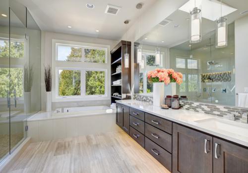Contemporary master bathroom features a dark dual vanity cabinet glass walk-in shower drop-in tub and open cabinets filled with shelves. Northwest USA